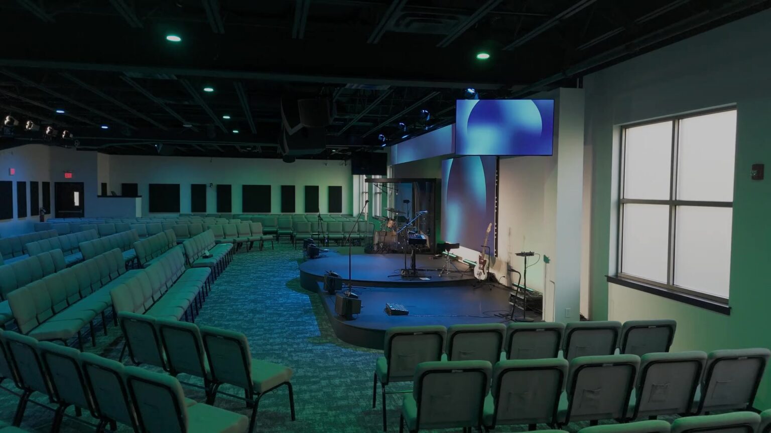 Drone orbit through the Next Community Church worship center, stage washed in teal light