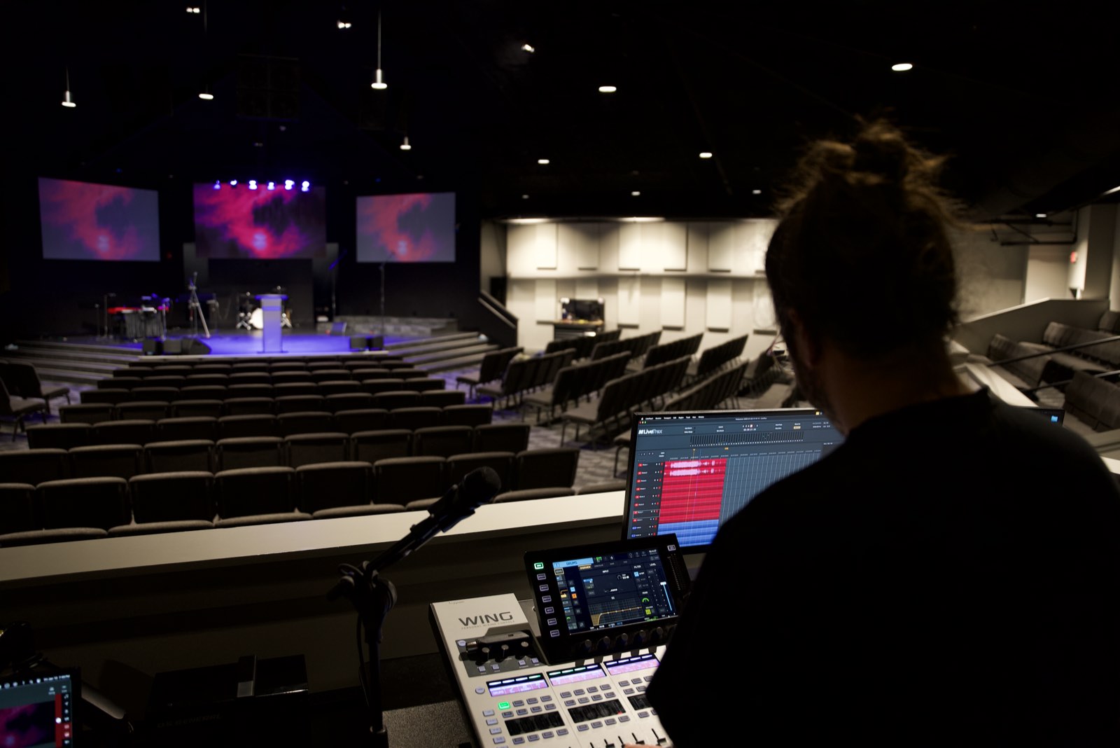 Operator mixing on the Behringer WING console at front of house, looking toward the stage at Faith Covenant Church of God