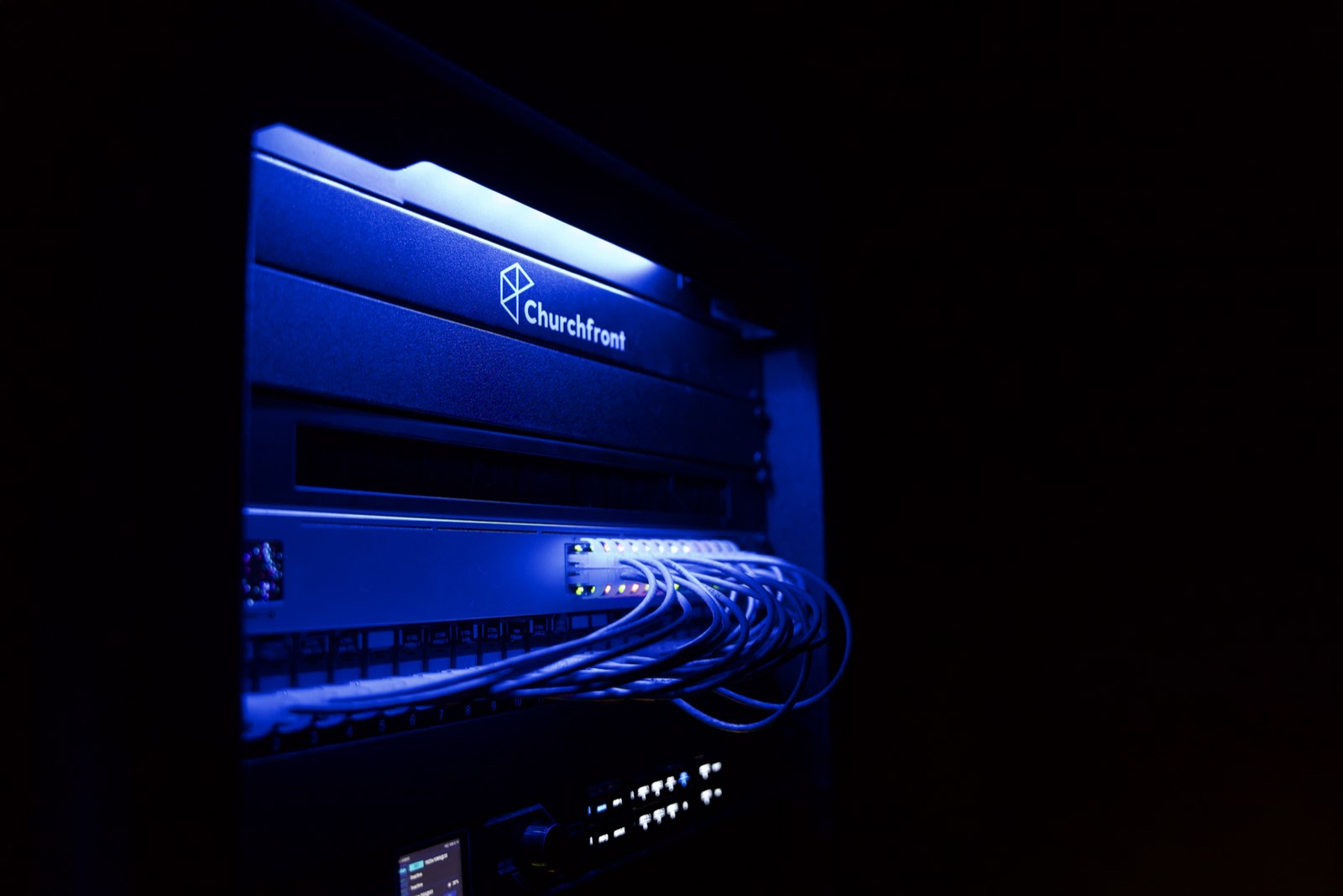 Churchfront equipment rack with patched network cabling lit in blue at Faith Covenant Church of God