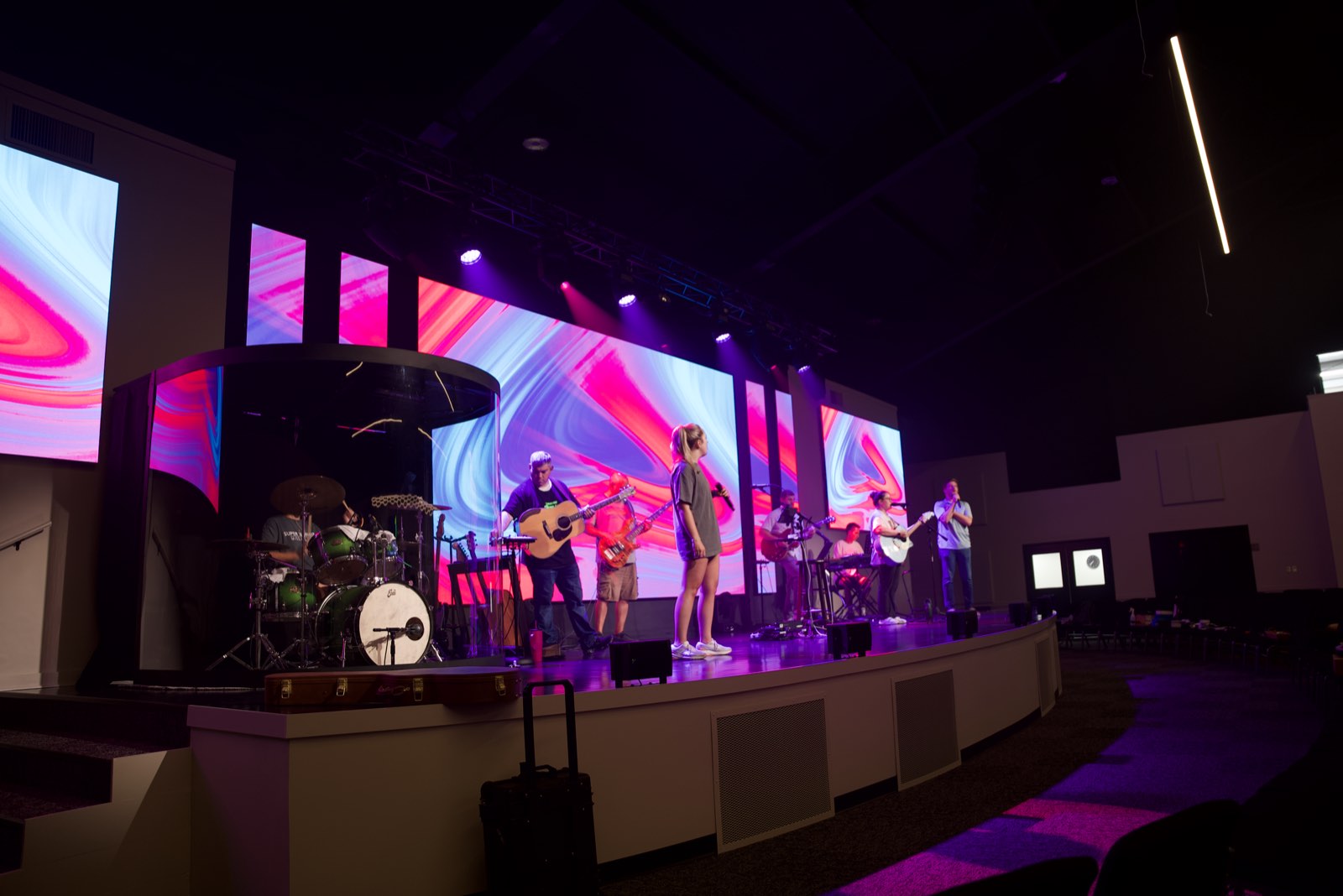 Worship band on the First Baptist Church Pontotoc stage with the drum kit in its enclosure and LED walls behind
