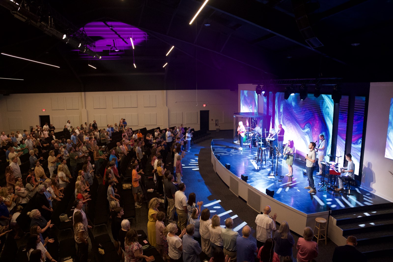 Full worship center at First Baptist Church Pontotoc during worship, with the band on a curved stage in front of LED walls