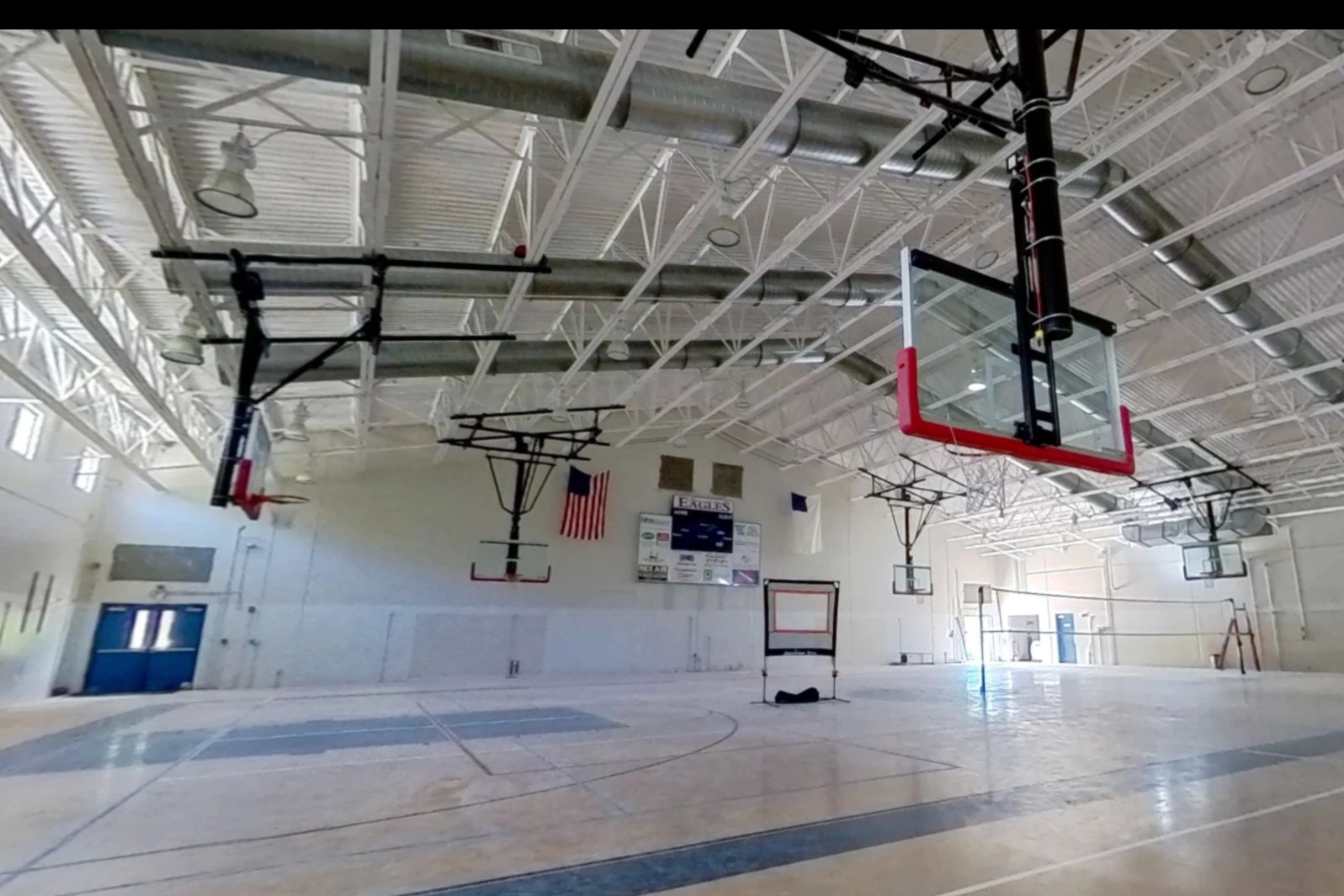 Island Community gym before its conversion, with basketball hoops, open trusses, and a hard floor.