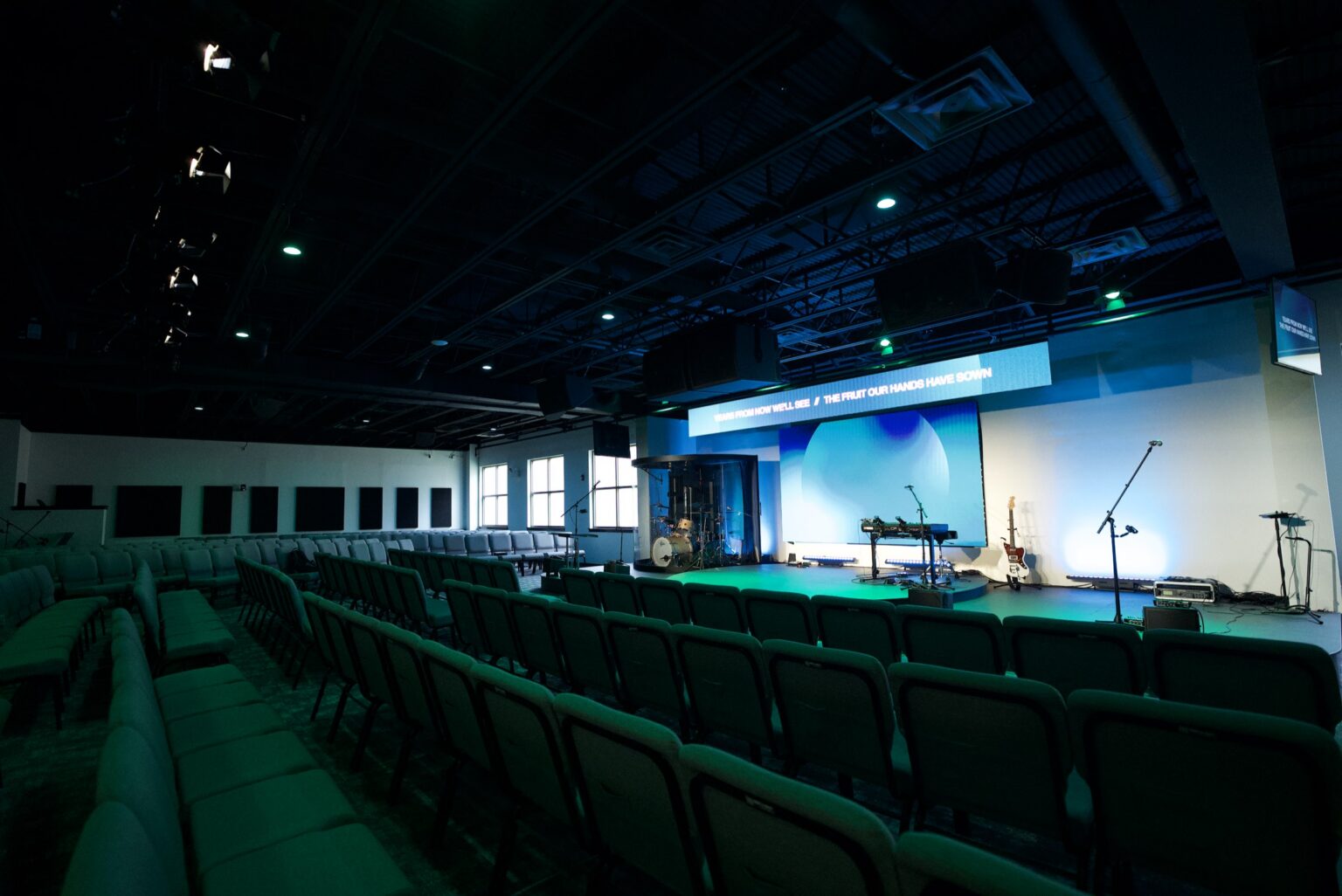 Church worship center with stage lighting and a lyric banner above the center screen