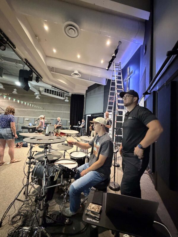 A Churchfront tech coaching a drummer on stage at North Metro Church