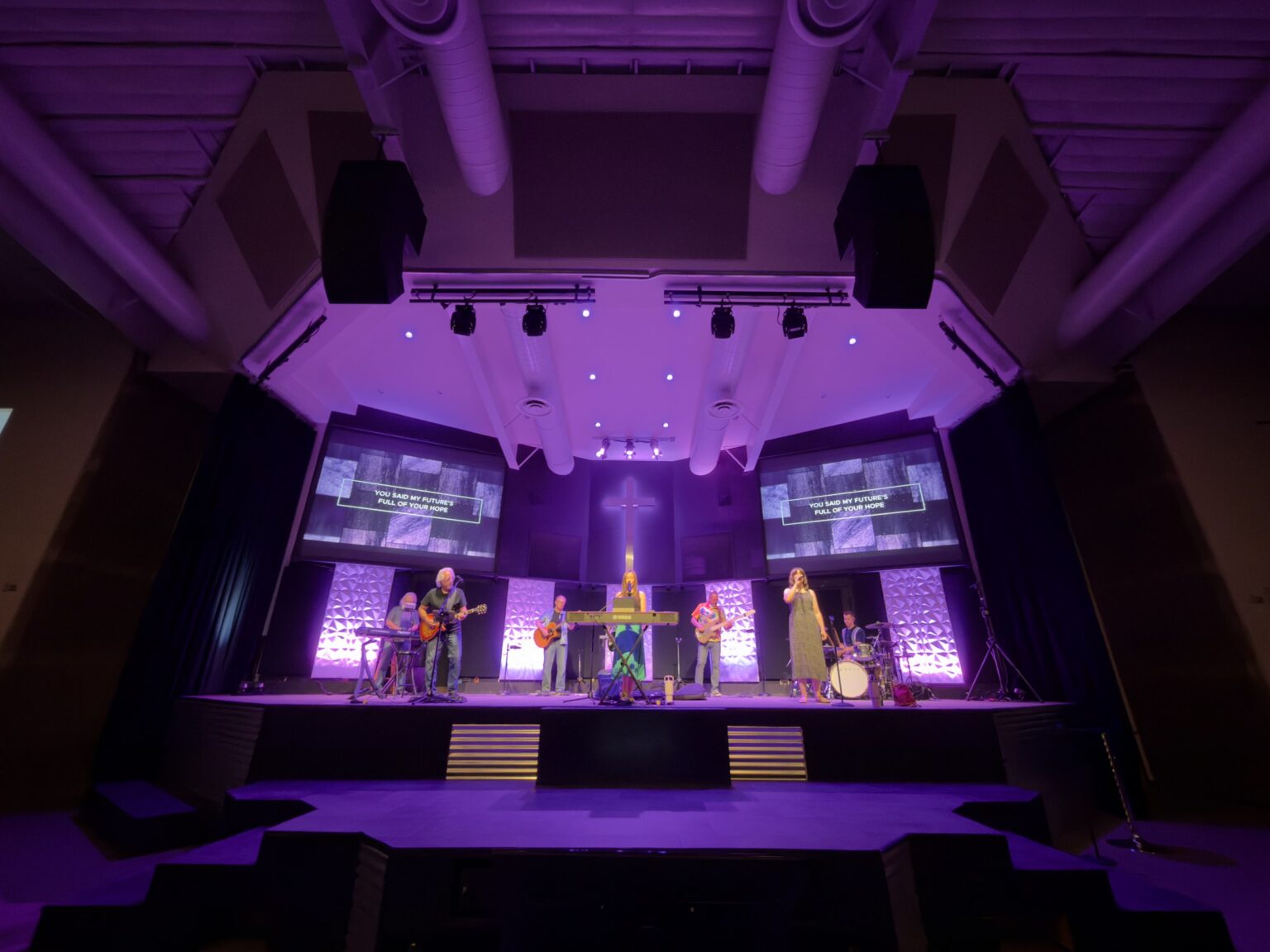 Church platform lit for worship with front light, stage wash and lit scenic panels