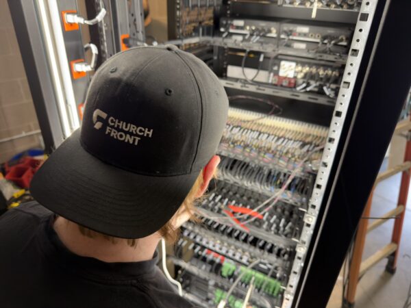 Technician terminating a punch-down patch field in a church AV rack
