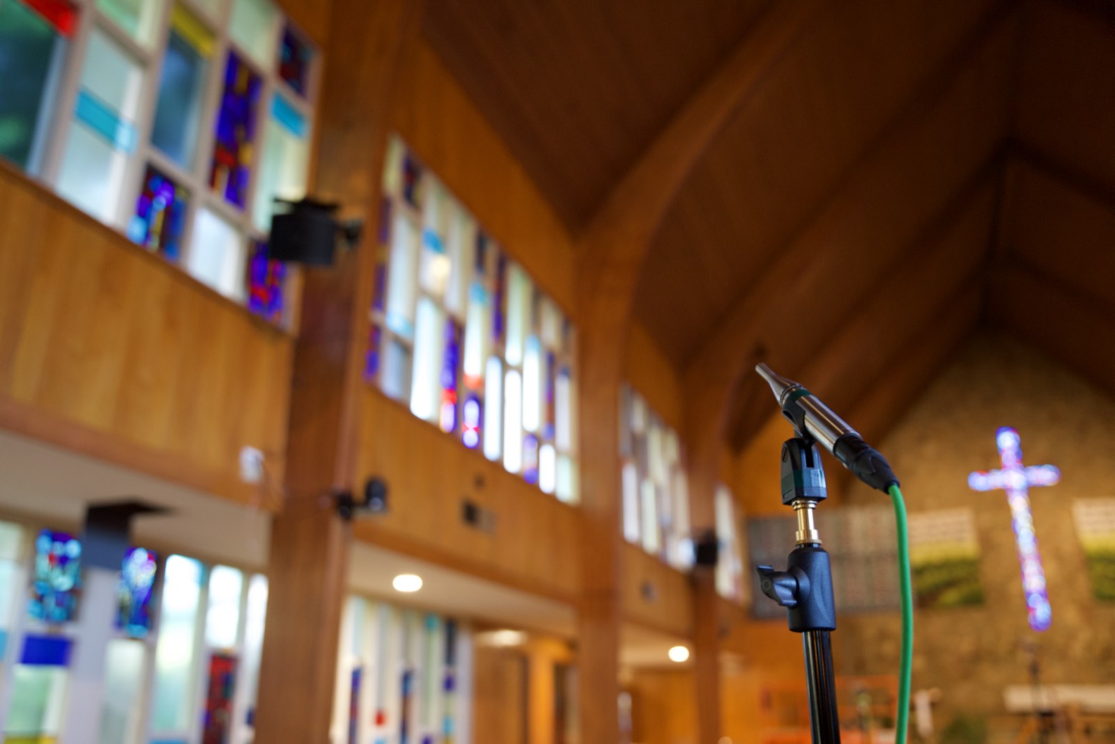 Measurement microphone on a stand in the sanctuary of St. John's Lutheran Church with speakers mounted along the stained glass wall
