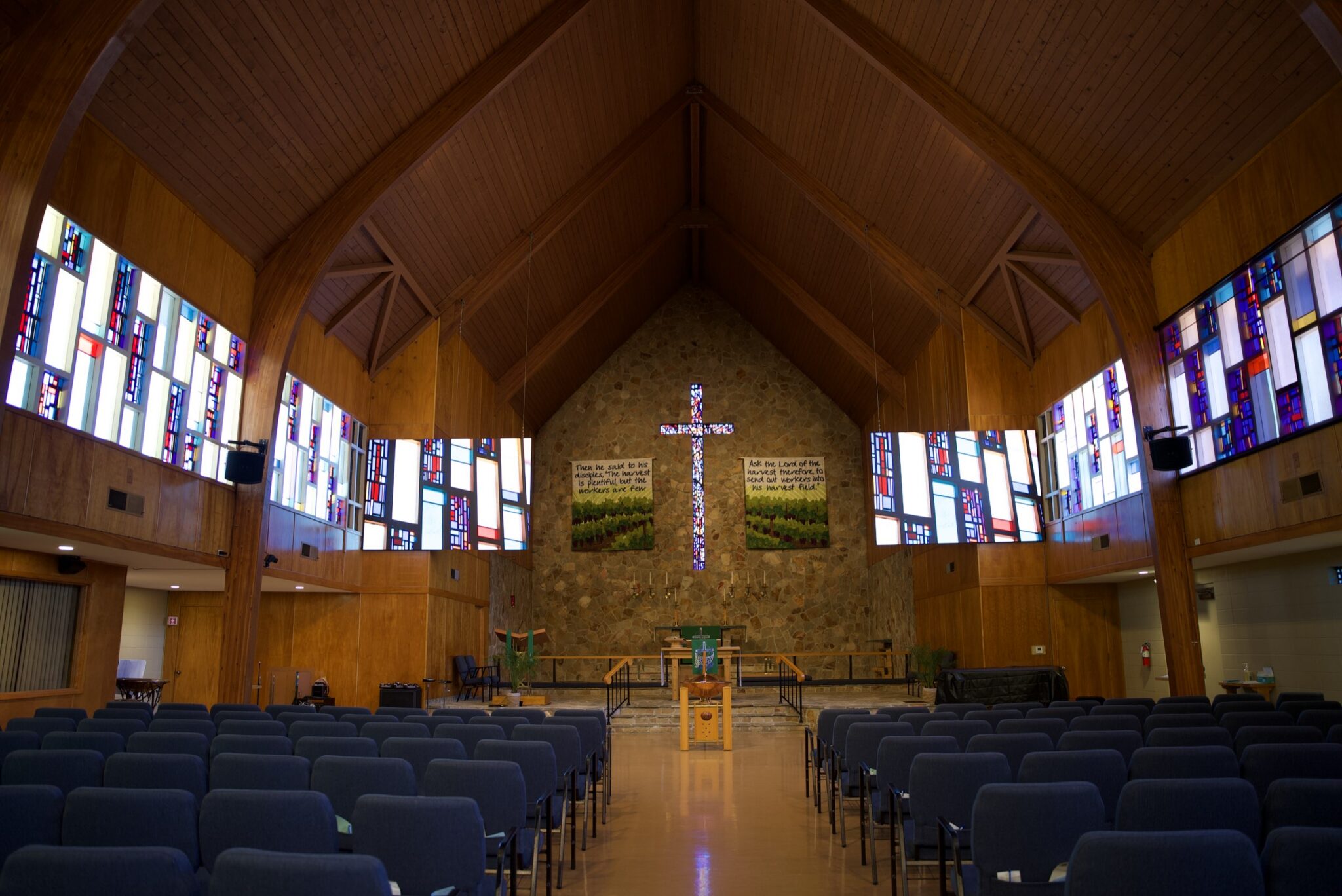 The St. John’s Lutheran sanctuary in Napa: timber A-frame ceiling, stained glass down both walls, and new LED screens either side of the cross