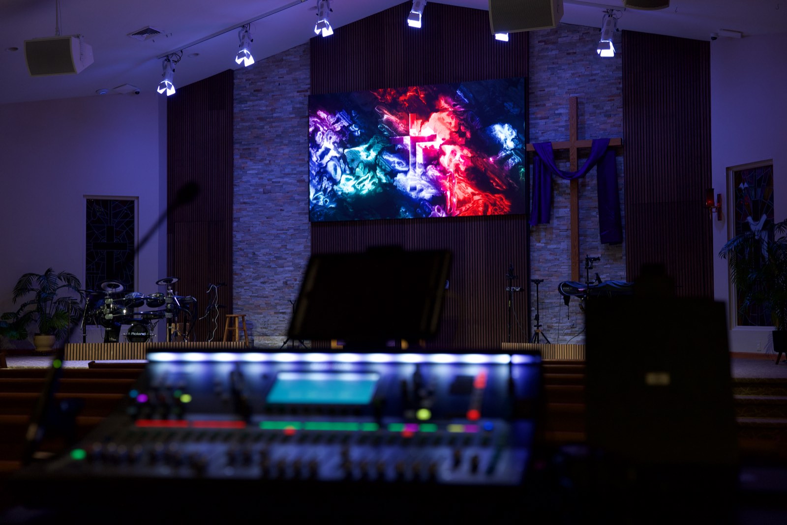 Lit mixing console in the foreground facing the stage and LED wall at Trinity Church